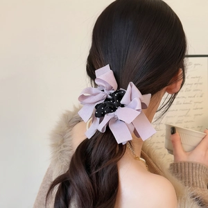 Dettaglio dell'elastico in seta viola chiaro con eleganti fiocchi a pois neri in nastro