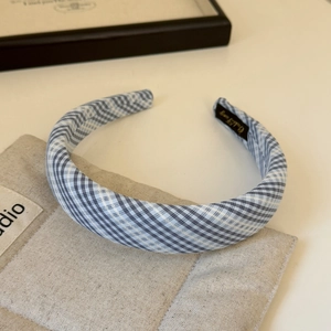 Detail view of blue plaid fabric headband with wide padded texture on soft linen cloth