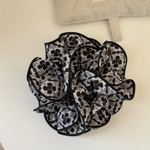Close-up of vintage black and white floral scrunchie with layered fabric and black edges