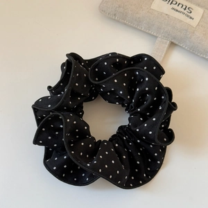 Macro detail of black and white polka dot scrunchie with soft pleated ruffle texture
