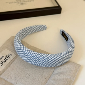 Detail of blue and white checkered headband with padded sponge on beige fabric background
