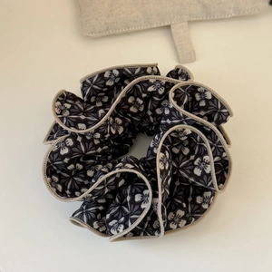 Detail of vintage floral scrunchie showing black and white fabric texture with beige hem