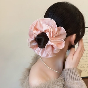 Detailed view of pink mesh scrunchie with pearls on a hair bun for elegant styling