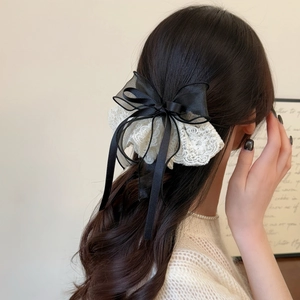 Elegant black satin hair bow with white lace trim and long ribbons on a ponytail
