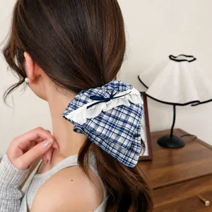 Blue plaid scrunchie with white lace edges and a dark blue bow on a ponytail
