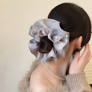 Detail of silver silk scrunchie with white pearls on elegant messy bun hairstyle