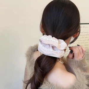 Chouchou à carreaux avec dentelle présenté sur une coiffure en queue de cheval