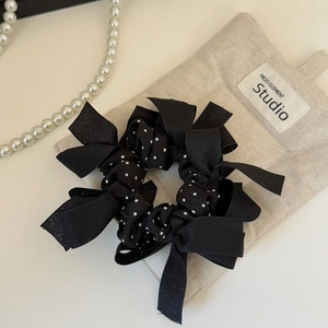 Dettaglio di un elastico per capelli nero a pois con fiocchi in tessuto mesh
