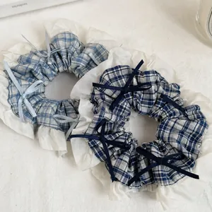 Detail of blue plaid hair scrunchies with white lace trim and small ribbon bows