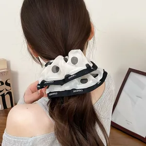 Detail showing elegant polka dot chiffon scrunchie with CHANGE ribbon on a ponytail