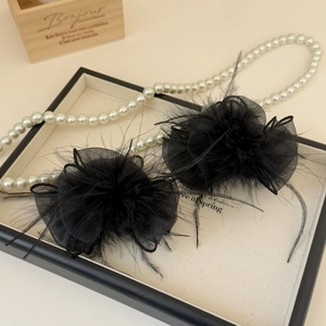 Close-up of black feather and tulle hair clips on a premium jewelry display tray