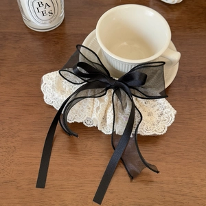 Elegant white lace bow hair clip with long black chiffon ribbons on a wooden table