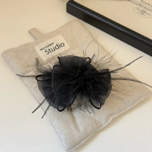 Close-up of black feather hair clip featuring soft ostrich plumes and mesh flower petals