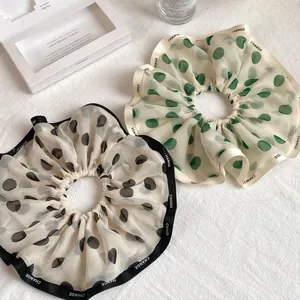 Detailed macro of chiffon polka dot scrunchies with letter printed contrast satin edges