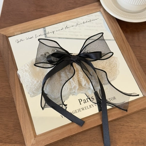Close-up of vintage black organza and white lace bow hair clip on a mirror tray