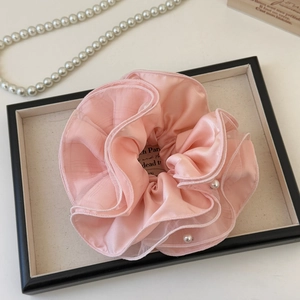 Detail of pink mesh scrunchie with layered fabric and pearls on jewelry display tray