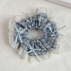 Detail of blue plaid fabric and white pleated lace scrunchie with small bows