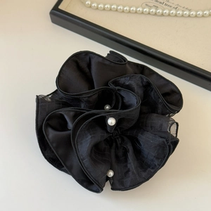 Detail of black satin flower scrunchie with three white pearls and elegant grid texture