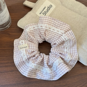 Détail d'un chouchou à carreaux roses avec dentelle et étiquette Hand Made sur bois