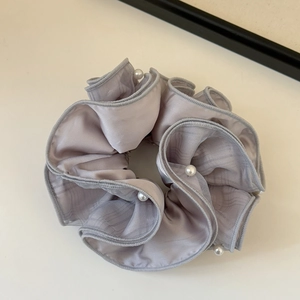 Detail of lavender satin scrunchie with soft pleats and elegant pearl embellishments