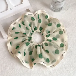 Detail showing elegant chiffon scrunchie with green polka dots and CHANGE letter ribbon