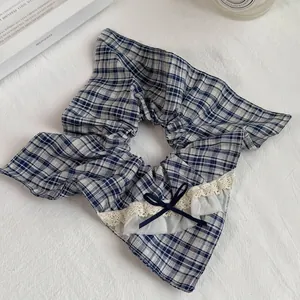 Detailed view of a blue plaid scrunchie with lace edges and a navy bow decoration