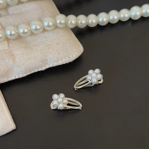 Detailed view of elegant silver flower hair clips with pearls on a black background