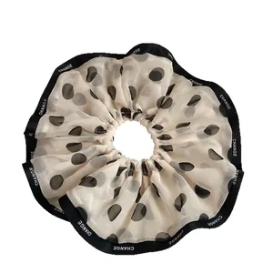 Elegant beige chiffon polka dot scrunchie with black Change lettering trim detail