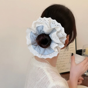 Chouchou à carreaux bleus avec bordure en dentelle blanche sur une coiffure en chignon