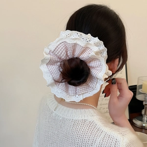 Chouchou géant à carreaux roses avec bordure en dentelle sur un chignon bas élégant