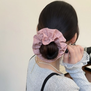 Chouchou à carreaux roses pour femmes présenté sur un chignon bas avec détails stylés