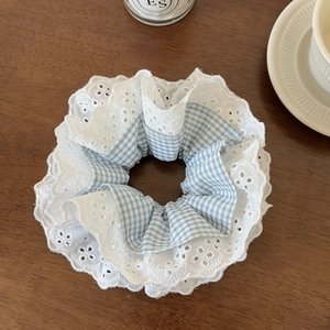 Détail de chouchou en dentelle blanche et carreaux bleus sur fond en bois