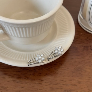Detailed close-up of pearl flower hair clips on a ceramic saucer with soft lighting