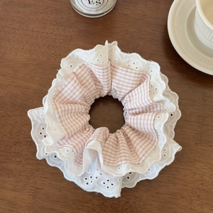 Gros plan d'un chouchou à carreaux roses avec bordures en dentelle sur table bois