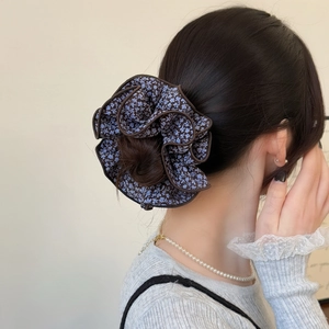 Floral oversized hair scrunchie with dark base and blue flowers on model's ponytail