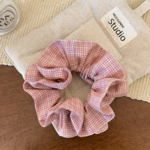 Détail du chouchou à carreaux rose et blanc avec texture volantée sur lin beige