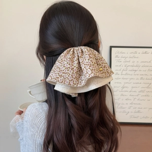 Détail d'une pince à cheveux à motif floral avec double couche et logo doré