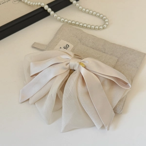 Vue détaillée du nœud en satin et organza crème avec un élégant pendentif doré