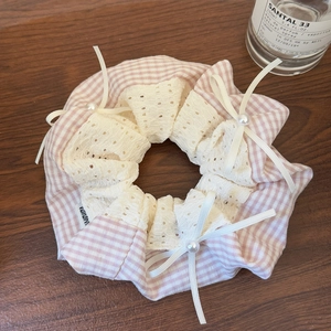 Detail of pink plaid scrunchie with lace trim, white ribbon bows, and pearl accents