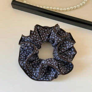 Close-up of brown floral scrunchie with blue flower pattern and stitched edge details