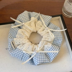 Detail of blue plaid scrunchie with white lace trim, ribbon bows and pearl accents