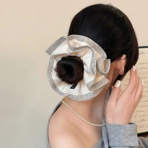 Close-up of double-layered scrunchie with tweed trim shown on a low hair bun