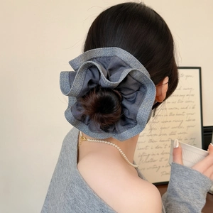 Elegant denim blue scrunchie with silver trim worn on a high bun hairstyle for women