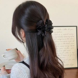 Elegante fermaglio per capelli con fiori in tessuto nero su lunghi capelli mossi e ricci