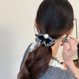 Plaid ruffle scrunchie with faux pearl accent worn in a ponytail for elegant hair styling