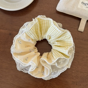 Detail of contrast plaid hair scrunchie with lace edges on a rustic wood table