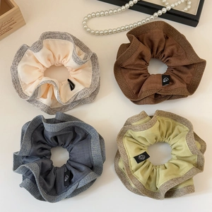 Set of four layered scrunchies in beige, grey, mocha, and olive green with tweed texture