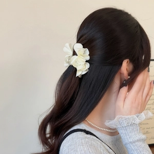Dettaglio del fermaglio a fiore in chiffon bianco crema indossato per un'acconciatura
