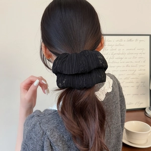 Elegant black pleated mesh scrunchie for women shown on a ponytail in a cozy setting