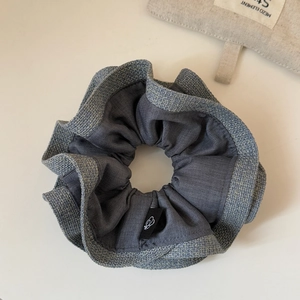 Macro shot of grey double-layered scrunchie with metallic trim and butterfly label